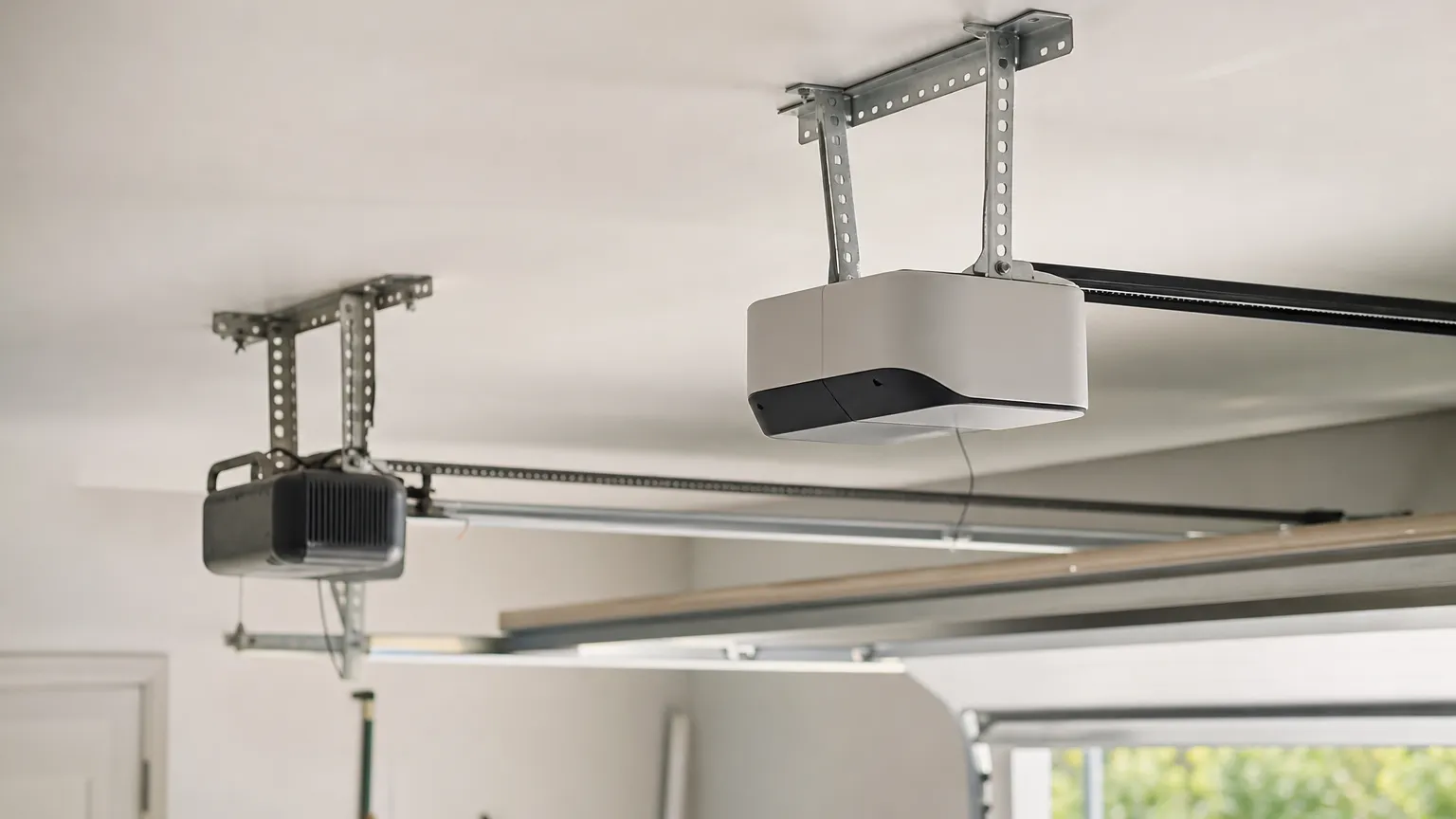 Garage door opener motor unit hanging from the ceiling of an attached garage with a belt rail and light cover