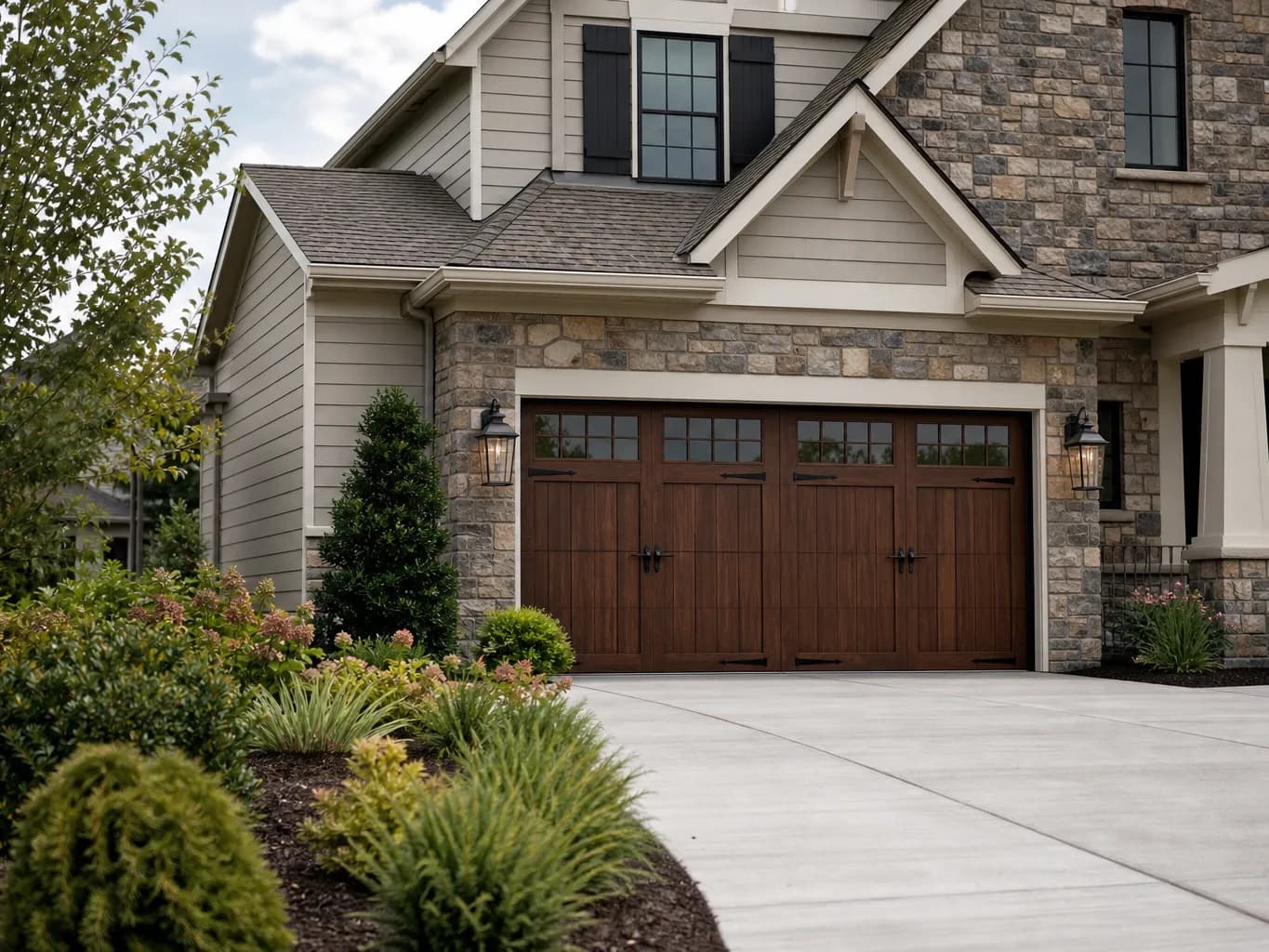 Stone and siding home with a wood tone carriage style double garage door and black hardware