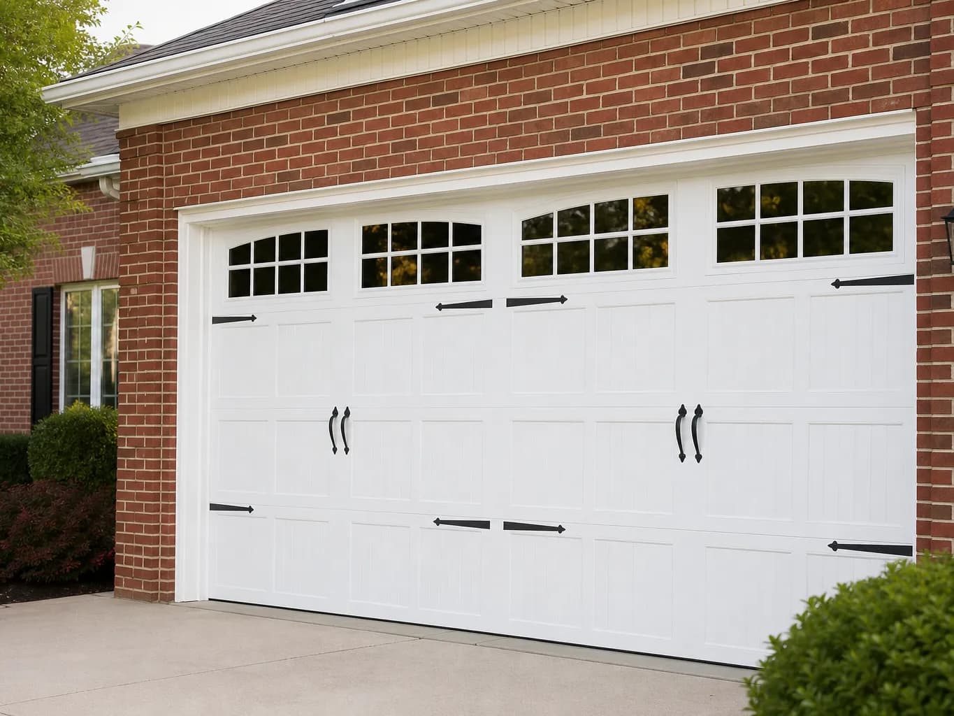 New raised panel steel garage door on a two car garage of a brick home with green hills behind it