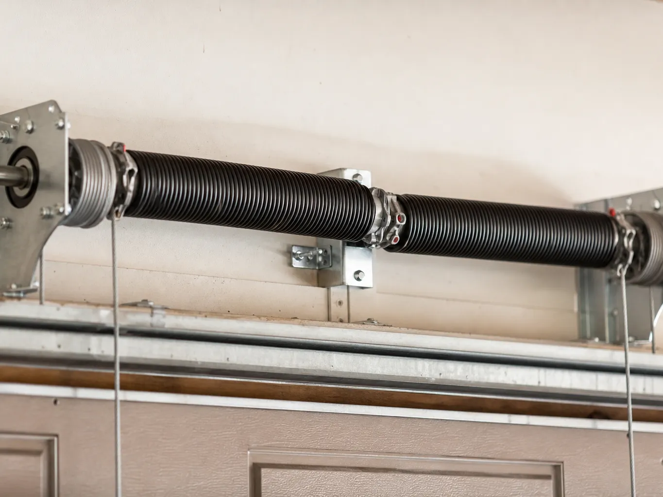 Close view of a torsion spring on a steel shaft above a residential garage door